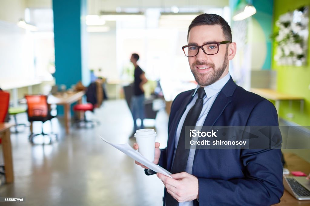Leader in formalwear Business leader with paper and drink looking at camera Adult Stock Photo