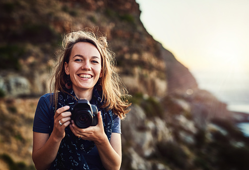 Portrait of a young woman taking photos with her camera outdoors