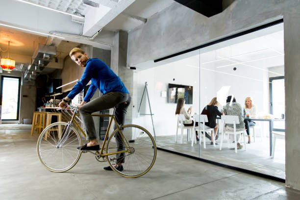 istock Young man sitting on a bicycle in a modern office 685862968