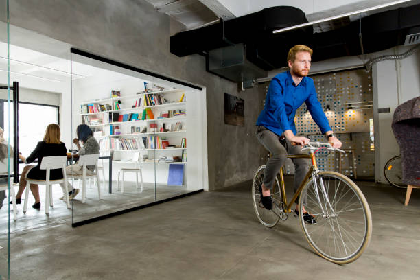 istock Young man sitting on a bicycle in a modern office 685862970