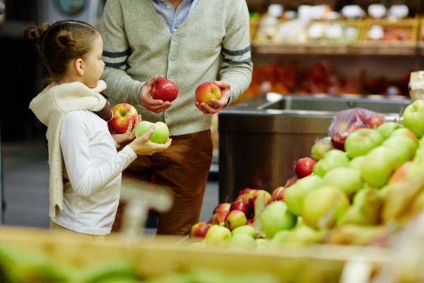 famiglia che acquista mele mature nel negozio di alimentari - market farmers market agricultural fair child foto e immagini stock