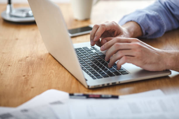istock businessman working on home office. Man sitting wood table and using contemporary notebook, texting message keyboard. 685864030