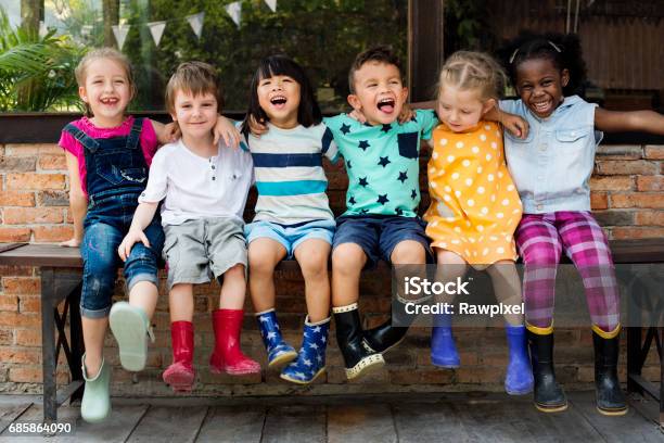 幼稚園の子供たちは笑顔で座って腕を組む - 子供のストックフォトや画像を多数ご用意 - 子供, 遊び心, 多民族