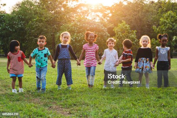 Niños De Pie En Una Fila Tomados De La Mano En Un Parque Foto de stock y más banco de imágenes de Niño