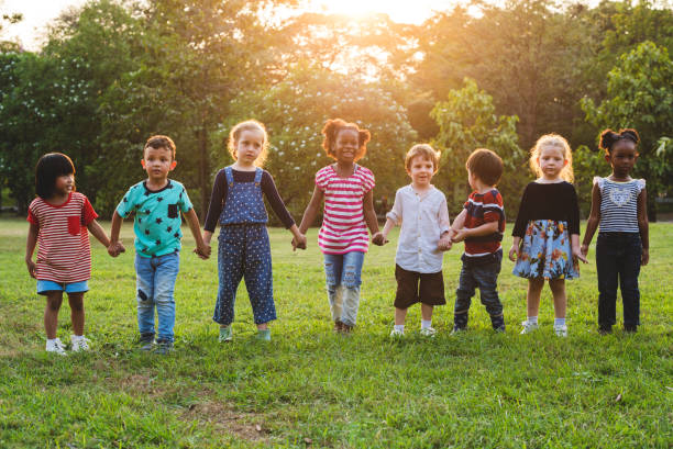 Kids standing in a row holding hands in a park Kids standing in a row holding hands in a park kids holding hands stock pictures, royalty-free photos & images