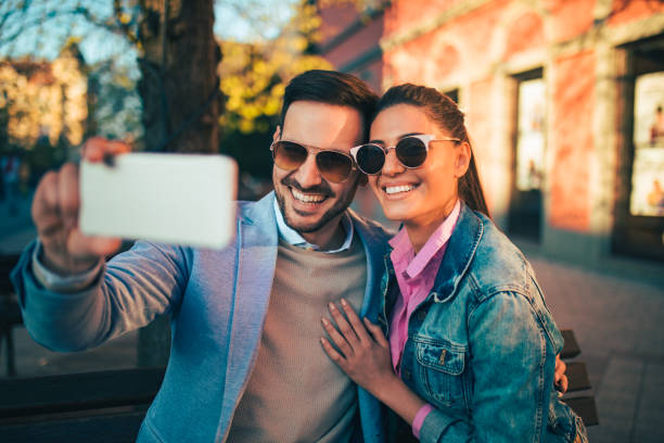 istock Couple in love sitting on bench and taking Selfie 685864408