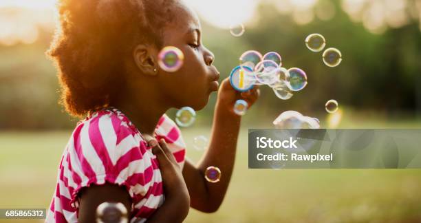 African Descent Girl Playing Blowing Bubble In A Park Stock Photo - Download Image Now