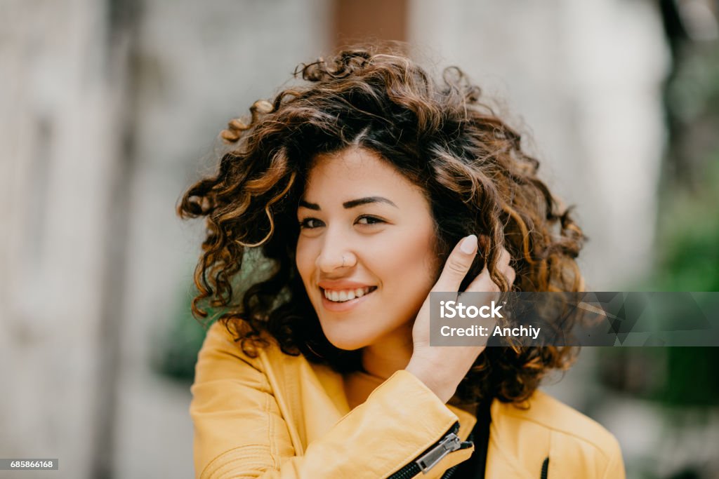 Beautiful young woman pulling fingers through her curly hair Nose Ring Stock Photo