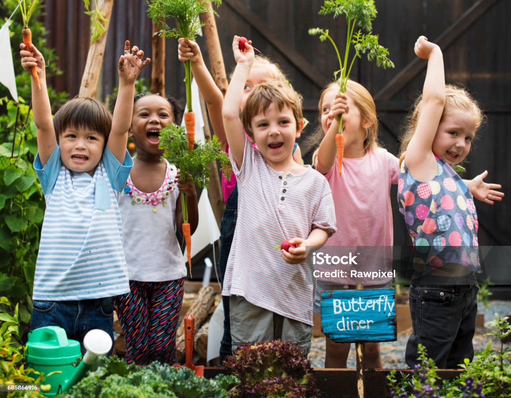 Children holding carrot in a garden Child Stock Photo