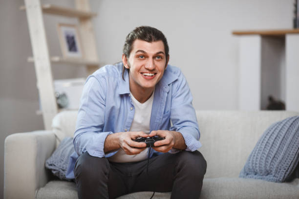 istock young man seated on a sofa playing video games inside his room 685867010