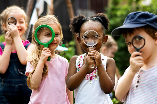 Group of kindergarten kids friends holding magnifying glass for explore