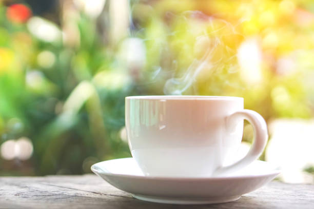 istock hot coffee cup on wooden table over green background 685869726