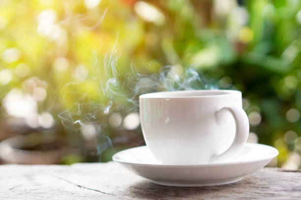 istock hot coffee cup on wooden table over green background 685870742