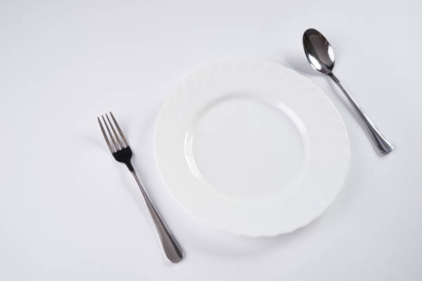istock A white plate with silver fork and spoon isolated on white background with copy space. Dinner place setting. Table Setting 685871356