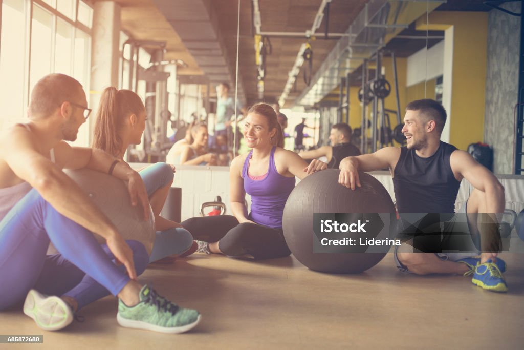 Group of people workout in healthy club. People having conversation after Pilates exercise with Pilates ball. Adult Stock Photo