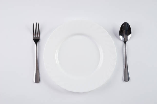 istock A white plate with silver fork and spoon isolated on white background with copy space. Top view. Dinner place setting. Table Setting 685872740