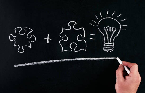 istock Businessmans Hand drawing puzzle on blackboard to explain business concept. Solving puzzle together. Drawing light bulb on blackboard. Combining the wisdom for developing new idea. 685873748