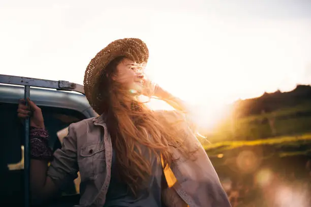 Beautiful blond woman sitting in the back of an old pick-up truck looking at nature