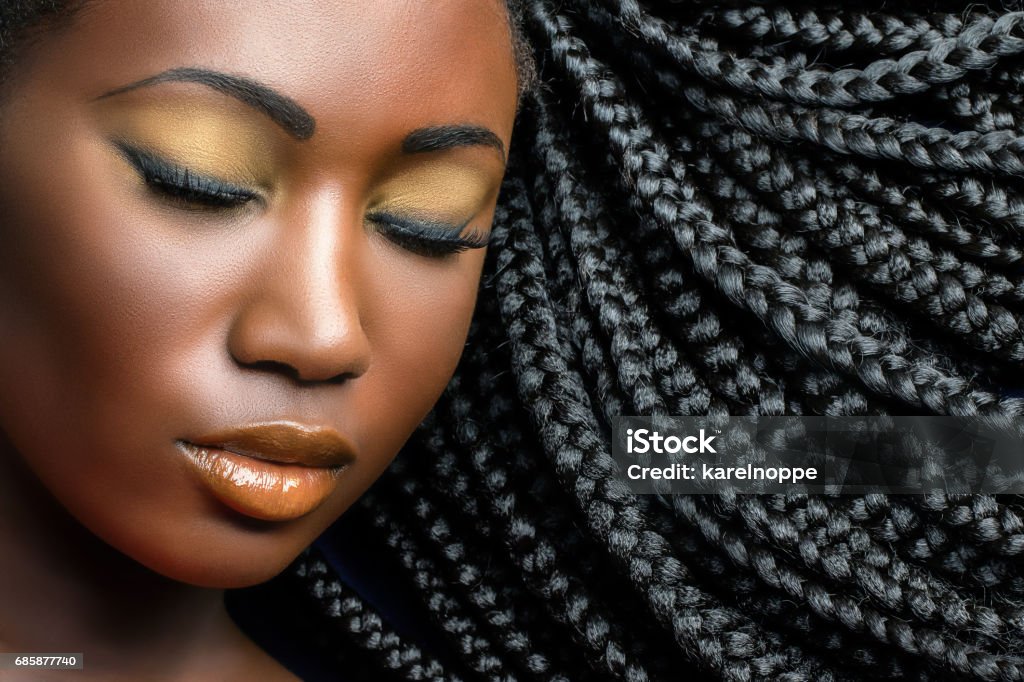 Dark girl beauty portrait with braids. Extreme close up beauty cosmetic portrait of young african woman  with eyes closed.Girl wearing professional make up showing black braided hairstyle. Hair Stock Photo