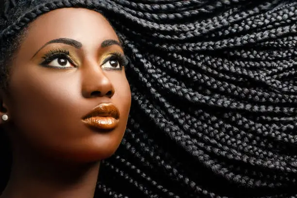 Close up cosmetic beauty portrait of african woman showing long black braided hairstyle.