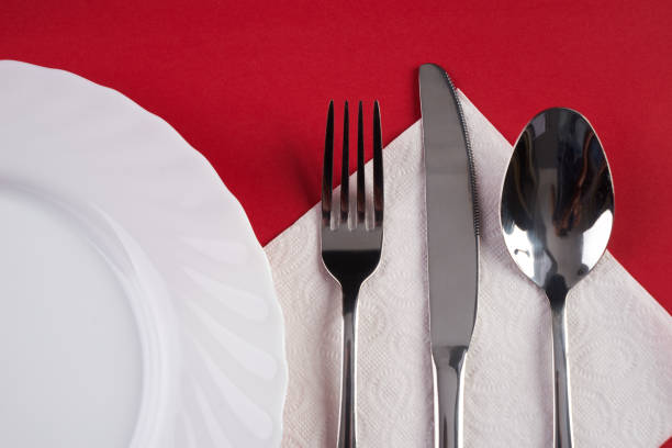 istock Empty white dinner plate with silver fork and Dessert Tablespoon, isolated on red tablecloth background with copy space. Table Setting, Folded Napkin. Dinner place setting 685878842