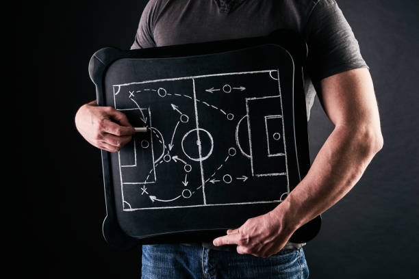 Hand of a football or soccer play coach drawing a tactics of football game with white chalk on blackboard at changing room during the time out Hand of a football or soccer play coach drawing a tactics of football game with white chalk on blackboard at changing room during the time out board eraser photos stock pictures, royalty-free photos & images