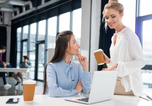 istock Smiling young businesswomen using laptop and talking at workplace 685880408