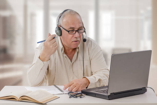 Young old man working as an online freelance teacher stock photo