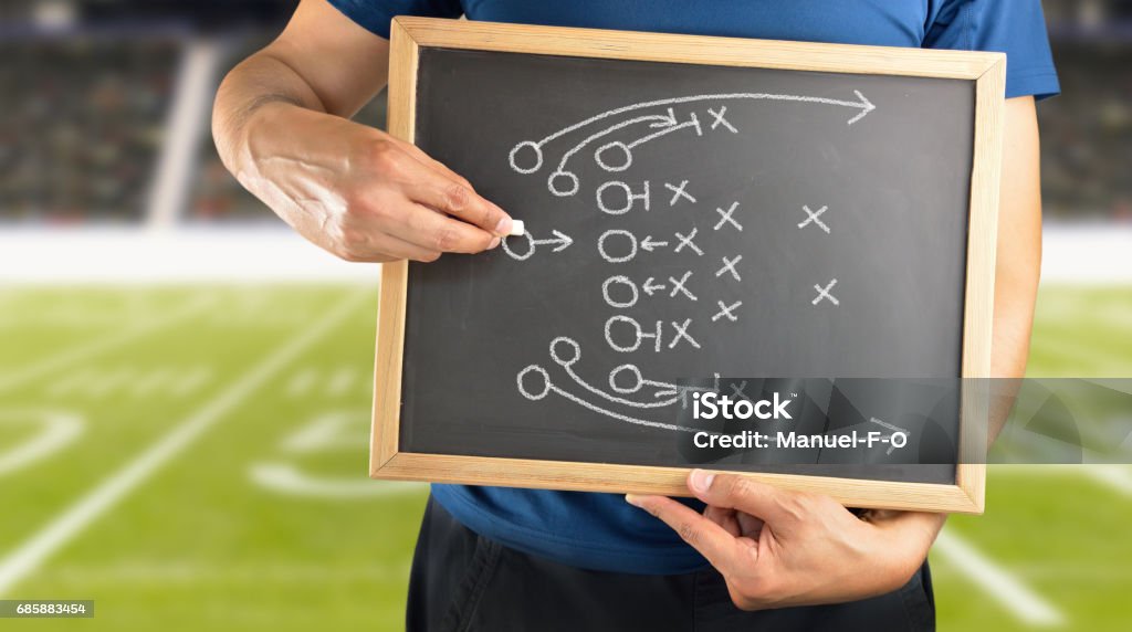 Drawing Attack Tactics hand of a american football coach drawing a tactics of  game with white chalk on blackboard at stadium background Adult Stock Photo