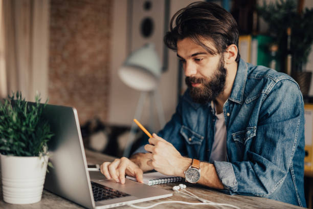 istock A man holds a pen and uses laptop 685883950