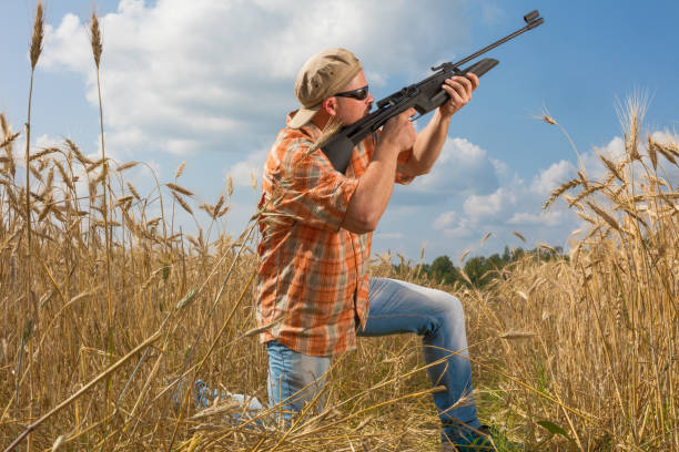 istock Hunter at cap and sunglasses aiming a gun at field 685885080