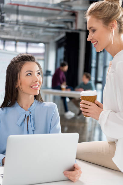 istock Smiling young businesswomen using laptop and talking at workplace 685885558