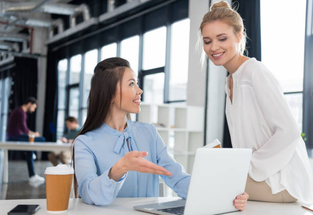 istock Smiling young businesswomen using laptop and talking at workplace 685885760
