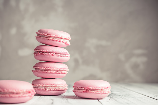 Stack of Raspberry pastel pink Macarons or Macaroons over grey concrete wall background