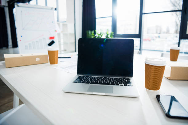 istock laptop computer, smartphone and coffee cups on workplace in empty office, small business office 685889146