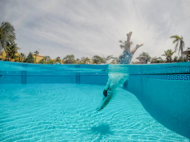 DCIM\\106GOPRO\\G0233090.Palm trees around the pool and men jumping into the water.