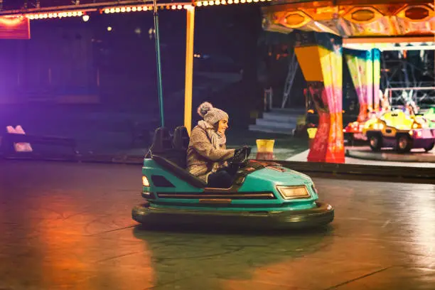 Young Woman Having Fun Riding Bumper Car in Amusement Park