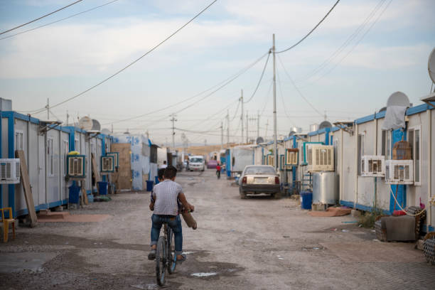 Christian IDP camp in Ankawa, Erbil, Iraq In Ankawa, a suburb of Erbil in northern Iraq, teenagers ride a bike down a street in a camp for Iraqi Christians who were displaced from their homes in Qaraqosh and other towns in the Ninevah plains. They were displaced by the 2014 ISIS advance, and it is unclear how many will return to their original homes even now that ISIS is pushed out. islamic state stock pictures, royalty-free photos & images