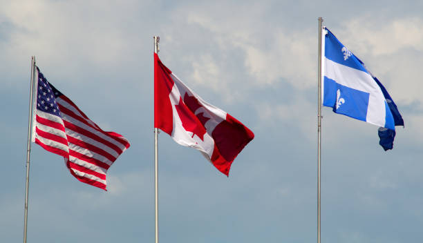 istock Canada, USA, and Quebec flags waving in the wind cloudy day 685901086