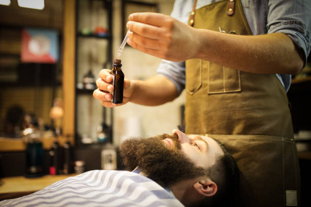 Barber putting beard oil to client stock photo