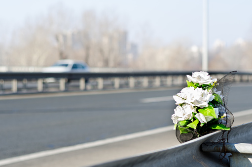 Artificial white roses flowers on the site of a traffic accident with a fatal outcome.