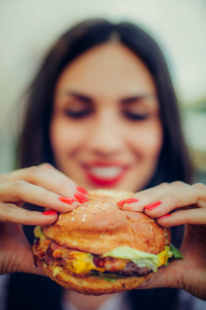 heureuse jeune femme manger savoureux fast-food burger - beautiful smiling vegetable calcium photos et images de collection