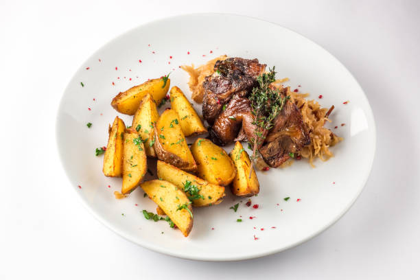 istock Pork knuckle with potatoes and cabbage on a white plate. Selective focus 685976800
