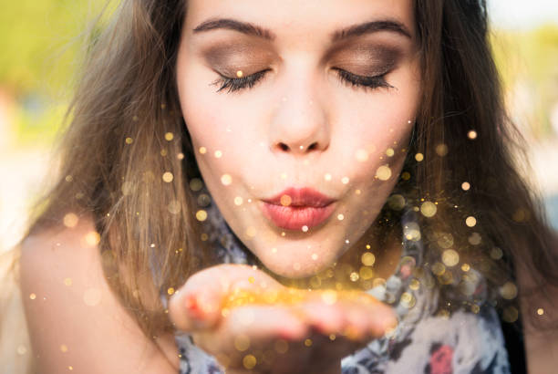 Making a wish A young woman closing her eyes as she blows golden confetti from her hand, and makes a wish. magical equipment stock pictures, royalty-free photos & images