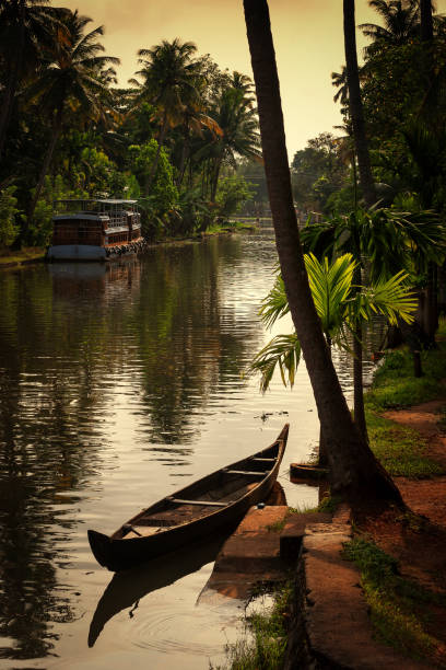 a canoe parked at sides of backwater canal on a partial cloudy afternoon at alleppey in kerala - kerala imagens e fotografias de stock