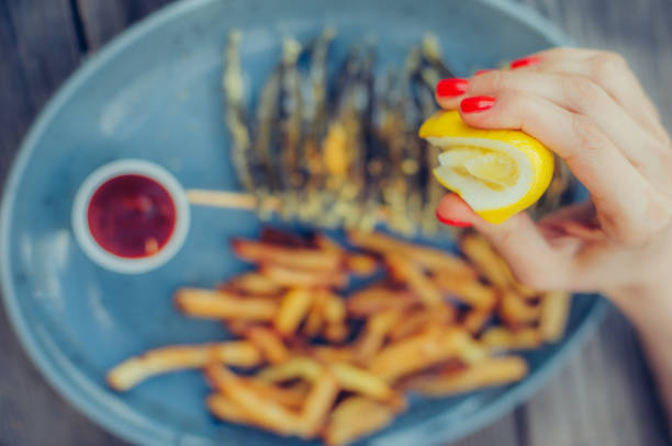 istock Woman squeeze lemon on portion of fish in a restaurant 685982918