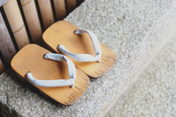 Geta or traditional Japanese footwear, a kind of flip-flops or sandal with an elevated wooden base held onto the foot with a fabric thong strap Geta or traditional Japanese footwear, a kind of flip-flops or sandal with an elevated wooden base held onto the foot with a fabric thong strap geta sandal stock pictures, royalty-free photos & images