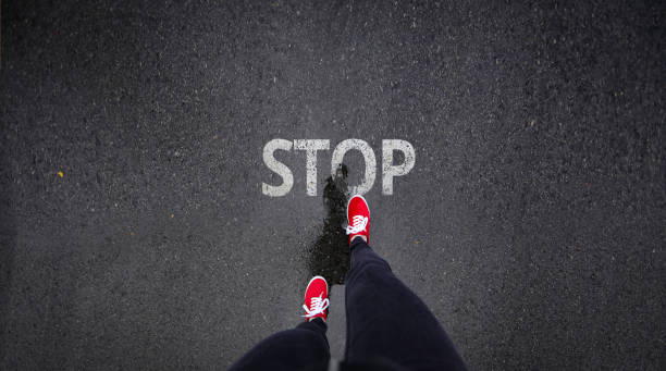 istock Red shoes standing next to stop sign painted on ground 686051118