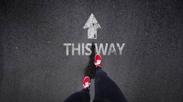istock Red shoes standing next to this way painted on road 686051120