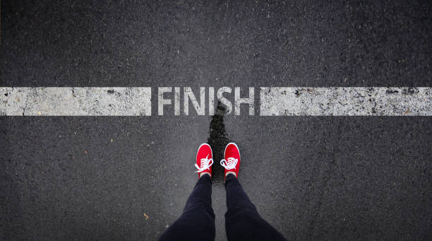 Red shoes standing next to finish line painted text Red shoes standing next to finish line painted text finish line photos stock pictures, royalty-free photos & images